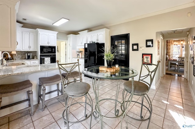 kitchen with sink, light tile patterned floors, black appliances, light stone countertops, and white cabinets