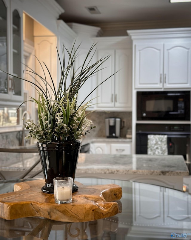 interior space featuring white cabinetry, ornamental molding, and black appliances