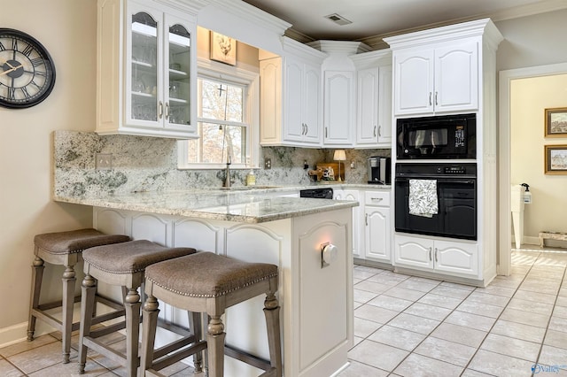 kitchen featuring light stone counters, backsplash, black appliances, and white cabinets