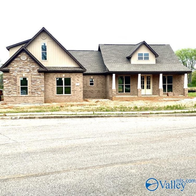 view of front of home with a shingled roof and brick siding