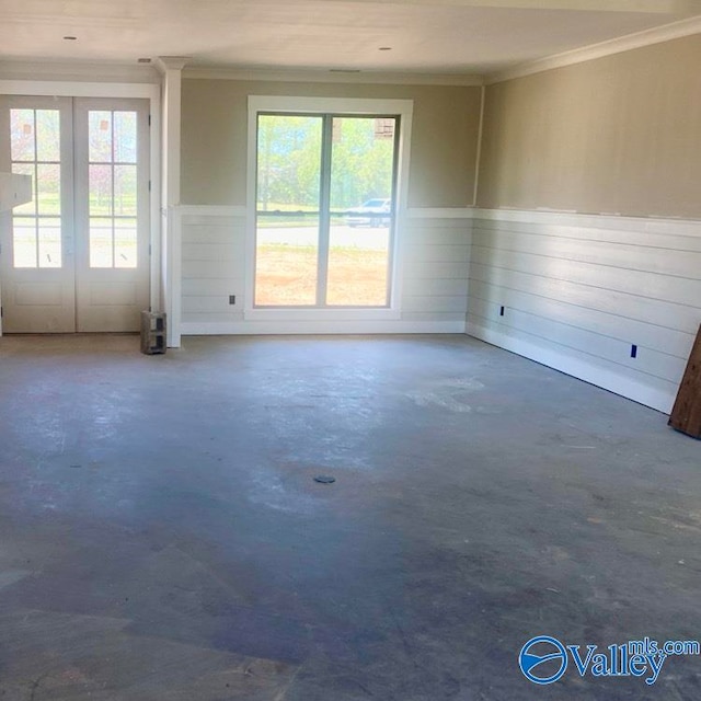 empty room featuring concrete flooring, crown molding, and a wealth of natural light