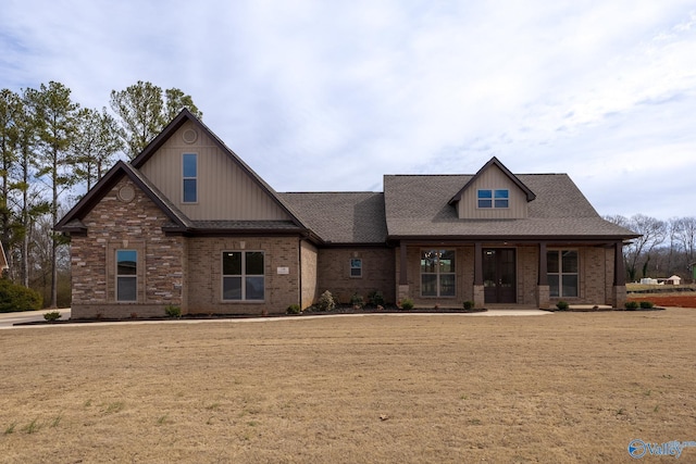 craftsman house featuring roof with shingles, a front lawn, and brick siding