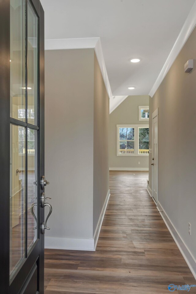 hall with lofted ceiling, wood-type flooring, and ornamental molding