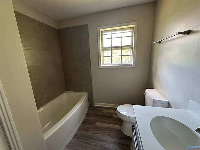 full bathroom featuring a textured ceiling, toilet, tiled shower / bath combo, hardwood / wood-style flooring, and vanity