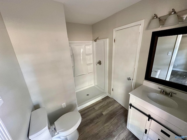 bathroom with a shower, wood-type flooring, vanity, and toilet