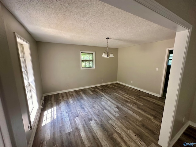 spare room with hardwood / wood-style floors, a textured ceiling, and an inviting chandelier