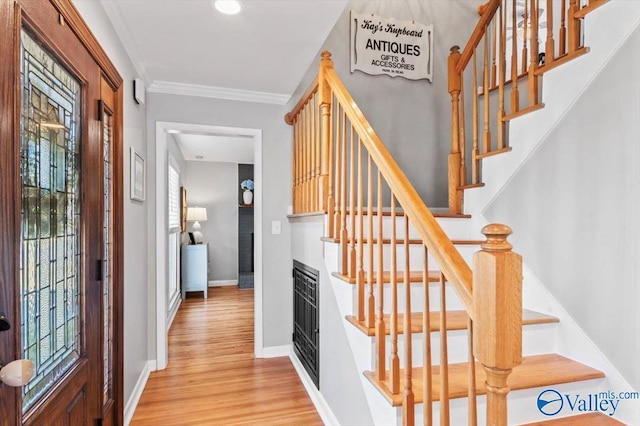 stairs with ornamental molding, a healthy amount of sunlight, baseboards, and wood finished floors