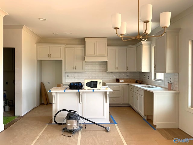 3017 Lisa Ln SE, Decatur, AL 35603 - kitchen featuring white microwave, a kitchen island, backsplash, a chandelier, and recessed lighting
