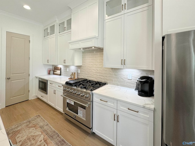 kitchen featuring appliances with stainless steel finishes, light wood-type flooring, light stone countertops, and white cabinets