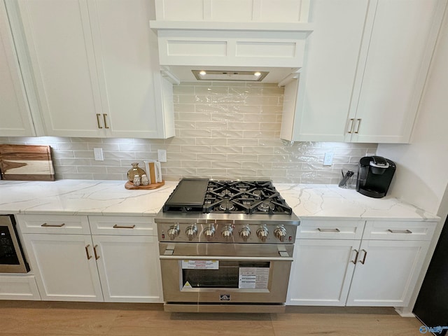 kitchen with decorative backsplash, white cabinetry, light stone countertops, stainless steel appliances, and light wood-type flooring