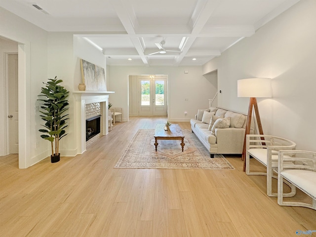 living room featuring beam ceiling, coffered ceiling, a fireplace, light hardwood / wood-style flooring, and french doors