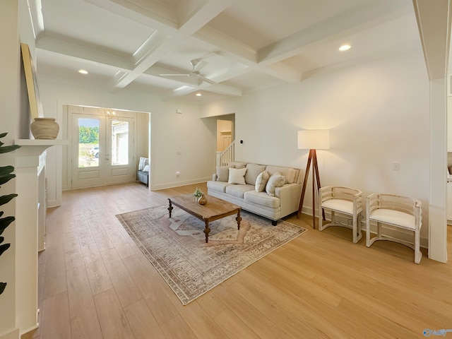 living room featuring light wood-type flooring, beam ceiling, coffered ceiling, ceiling fan, and french doors