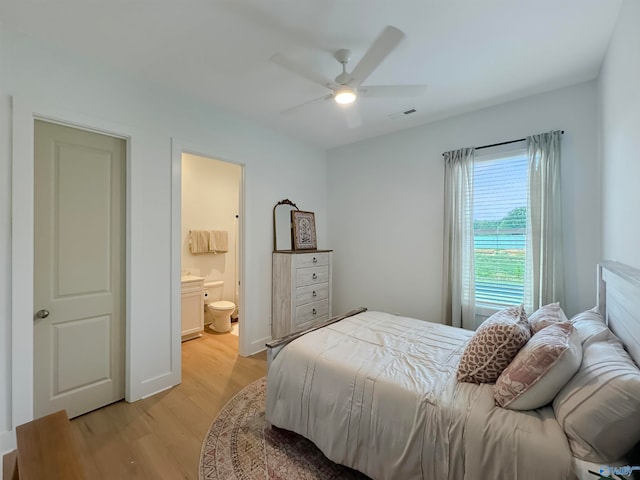 bedroom featuring light hardwood / wood-style floors, ensuite bath, and ceiling fan