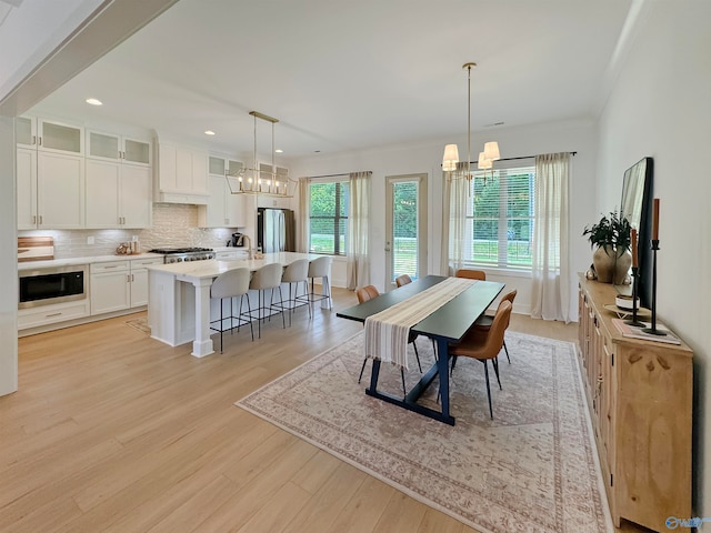 dining room featuring ornamental molding, an inviting chandelier, sink, and light hardwood / wood-style floors