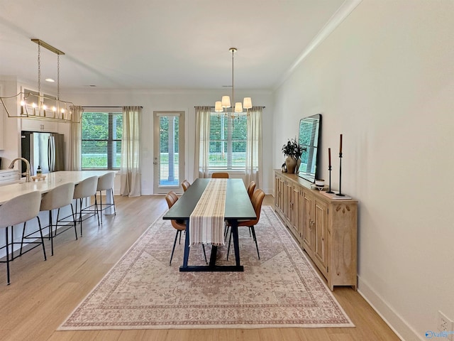 dining space with light hardwood / wood-style flooring, a notable chandelier, ornamental molding, and sink