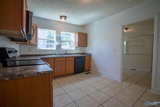 kitchen featuring dark countertops, a textured ceiling, a sink, light tile patterned floors, and stainless steel appliances