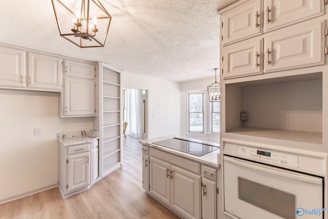 kitchen featuring oven, black electric cooktop, decorative light fixtures, light hardwood / wood-style flooring, and an inviting chandelier