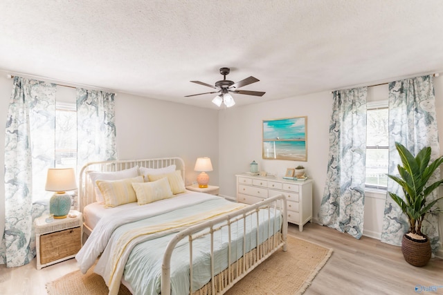 bedroom with light wood-type flooring, a textured ceiling, and ceiling fan