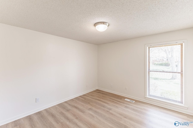 empty room featuring light wood-type flooring and a textured ceiling