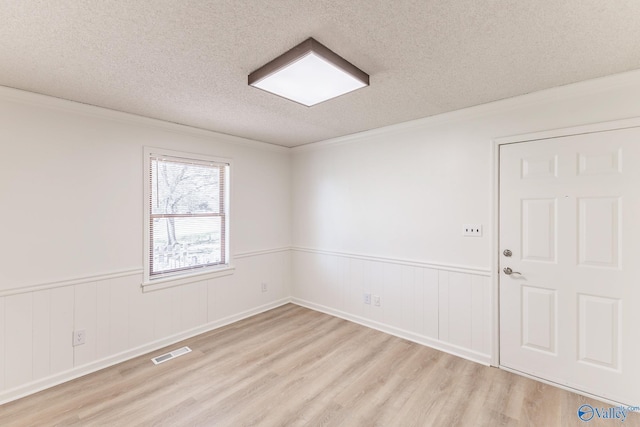 unfurnished room with light hardwood / wood-style floors, a textured ceiling, and ornamental molding