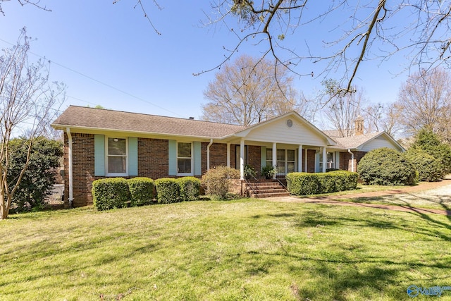 ranch-style home featuring covered porch and a front yard