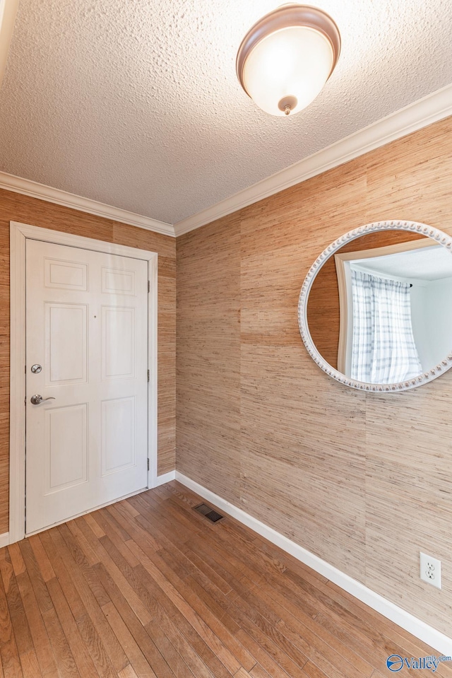 interior space with hardwood / wood-style flooring, a textured ceiling, and crown molding