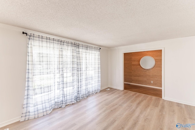 spare room with light hardwood / wood-style flooring and a textured ceiling