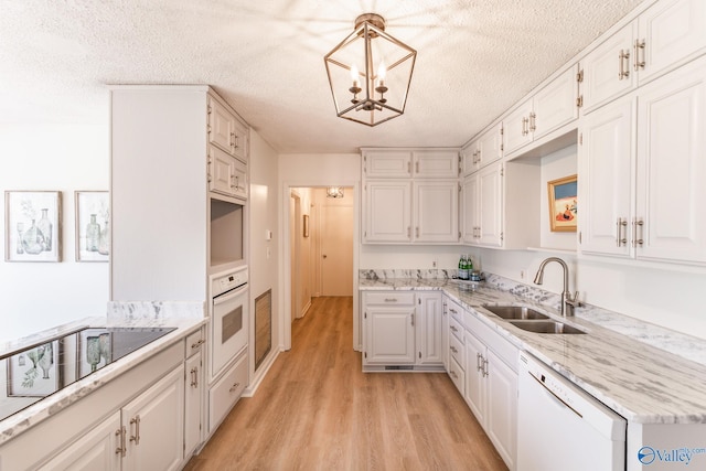 kitchen with decorative light fixtures, white appliances, and white cabinetry