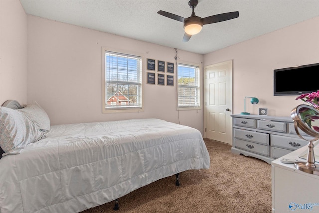 bedroom featuring ceiling fan, light colored carpet, and a textured ceiling