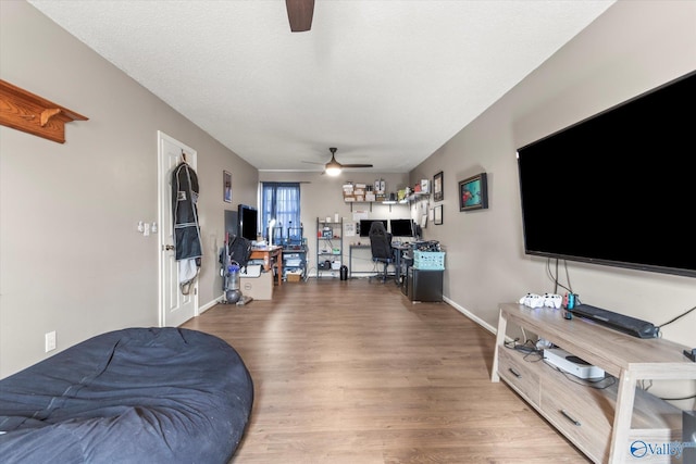 living room featuring a textured ceiling, wood-type flooring, and ceiling fan