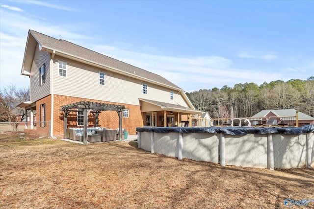 rear view of house with an outdoor hangout area, a pergola, a lawn, and a covered pool