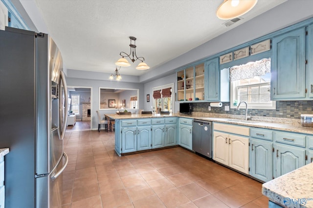 kitchen featuring sink, hanging light fixtures, stainless steel appliances, decorative backsplash, and kitchen peninsula