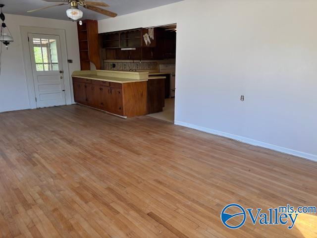 kitchen featuring ceiling fan, light wood-type flooring, open floor plan, and light countertops