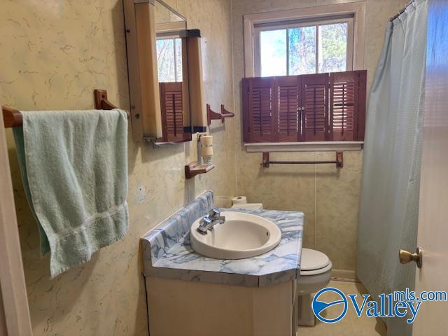full bath with plenty of natural light, toilet, wallpapered walls, and vanity