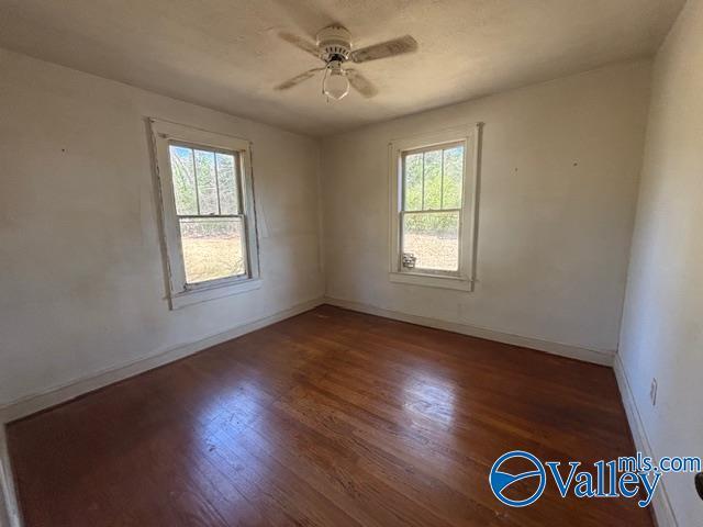 empty room featuring baseboards, ceiling fan, and wood finished floors