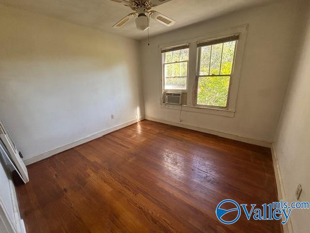 empty room with wood finished floors, cooling unit, a ceiling fan, and baseboards