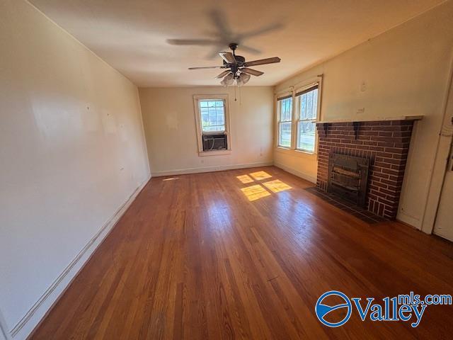 unfurnished living room featuring a fireplace, baseboards, ceiling fan, and wood finished floors