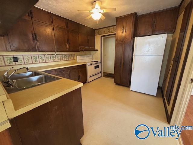 kitchen with dark brown cabinets, light countertops, white appliances, a ceiling fan, and a sink