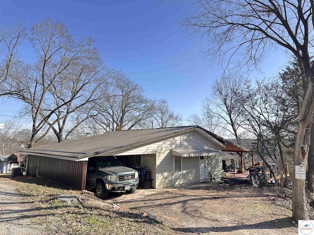 view of home's exterior with an attached carport and dirt driveway