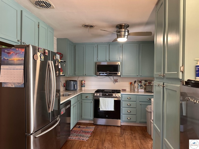 kitchen featuring a ceiling fan, visible vents, dark wood-style flooring, stainless steel appliances, and light countertops