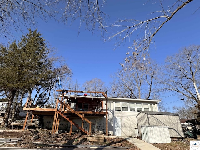 back of property with an outbuilding, stairway, and a wooden deck