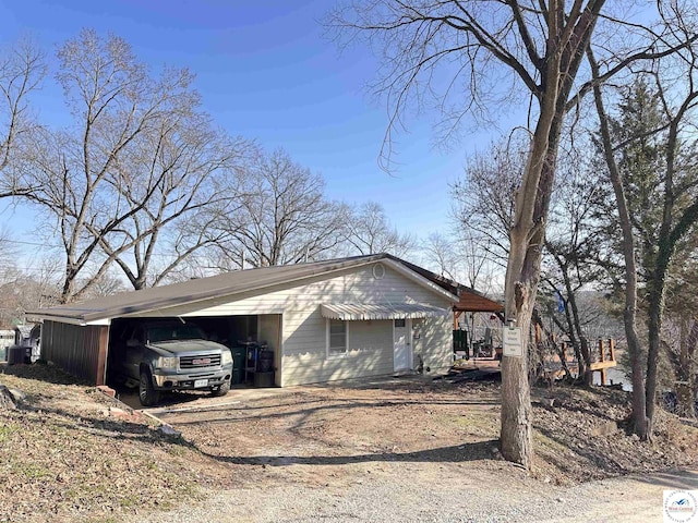 view of side of property featuring central air condition unit, a carport, and driveway