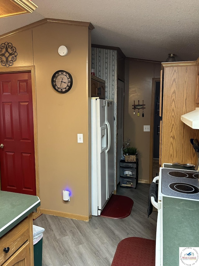 kitchen with range hood, a textured ceiling, white fridge with ice dispenser, light wood-type flooring, and baseboards