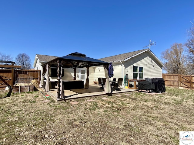 back of property with a fenced backyard, a wooden deck, and a gazebo