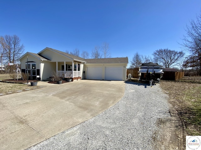 view of front facade featuring driveway, covered porch, and an attached garage