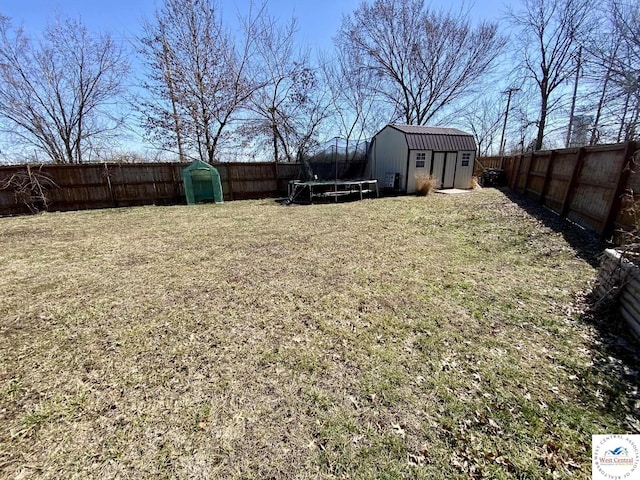 view of yard featuring an outbuilding, a shed, a trampoline, and a fenced backyard