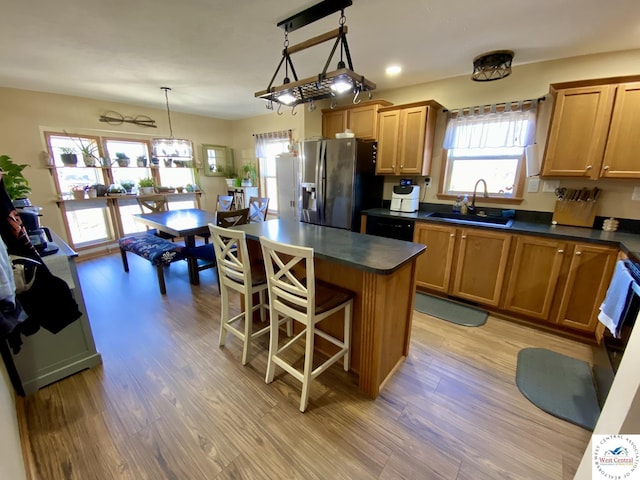 kitchen featuring a breakfast bar area, a sink, dark countertops, and stainless steel fridge with ice dispenser