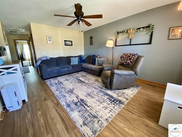 living area with a ceiling fan, visible vents, baseboards, and wood finished floors