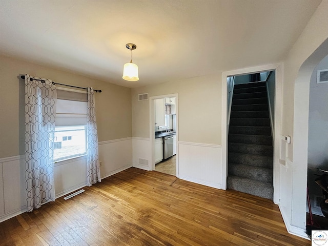 interior space with wood finished floors, wainscoting, visible vents, and stairs