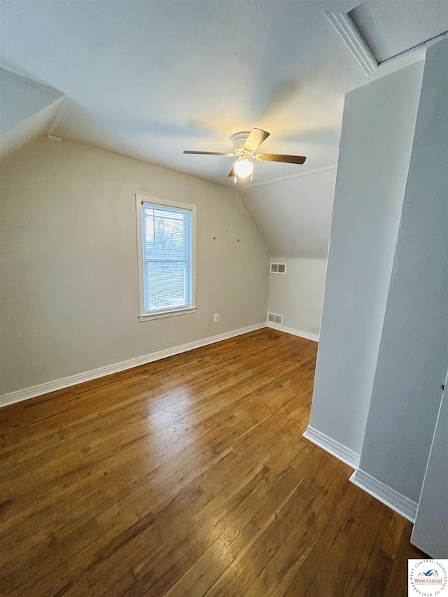 additional living space featuring ceiling fan, dark wood-style flooring, visible vents, baseboards, and vaulted ceiling